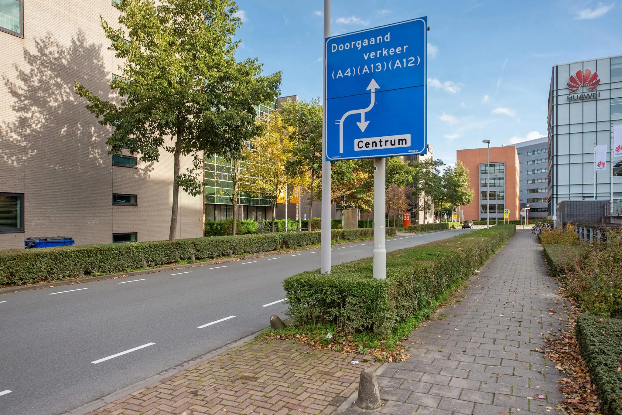 Verkeersbord met route-informatie langs de Laan van Vredenoord in een modern kantoorgebied met gebouwen van onder andere Huawei.